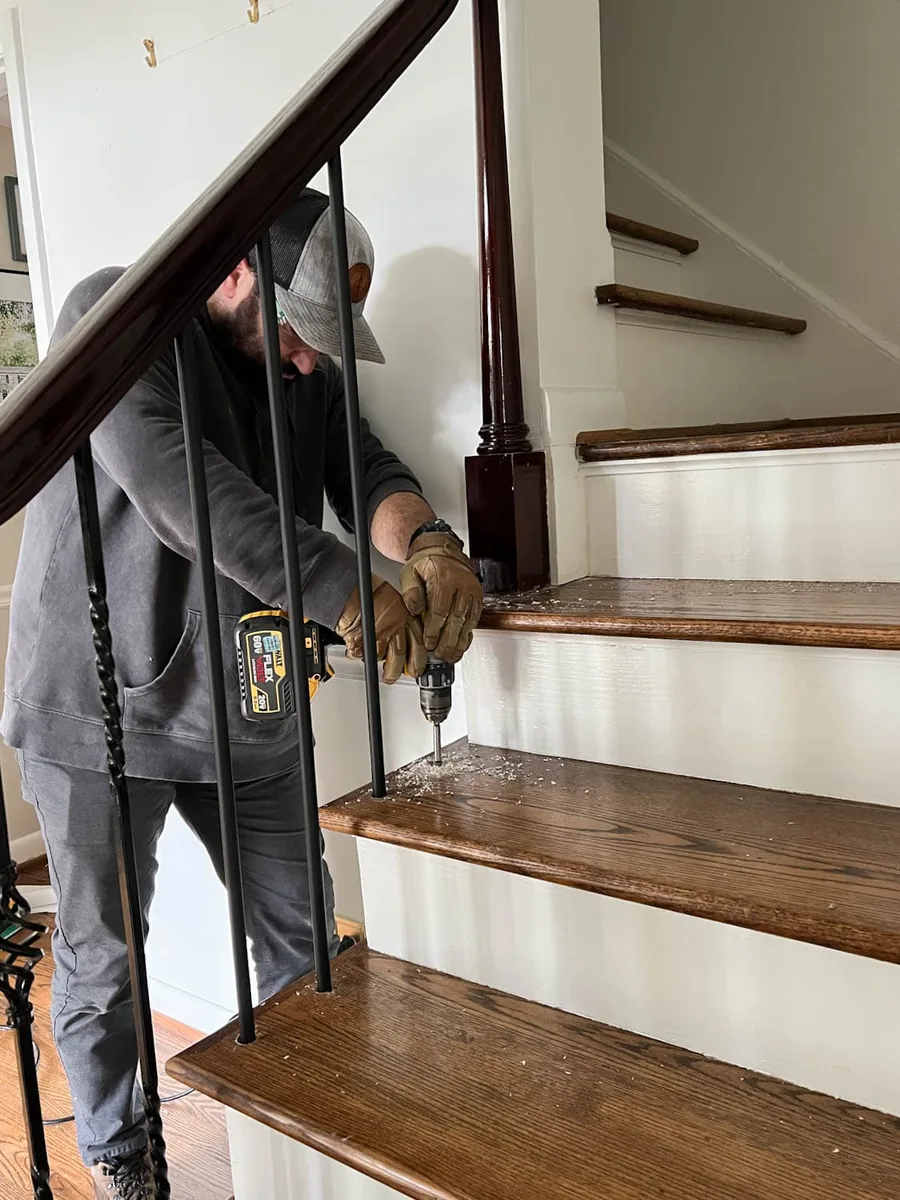 Installer replacing wood balusters with black iron balusters on a staircase in Manotick, Ottawa