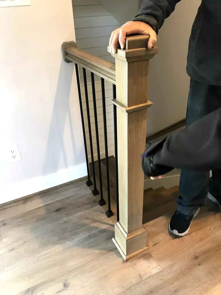 Box newel post and handrail with black metal balusters at the top of a staircase in Vanier, Ottawa
