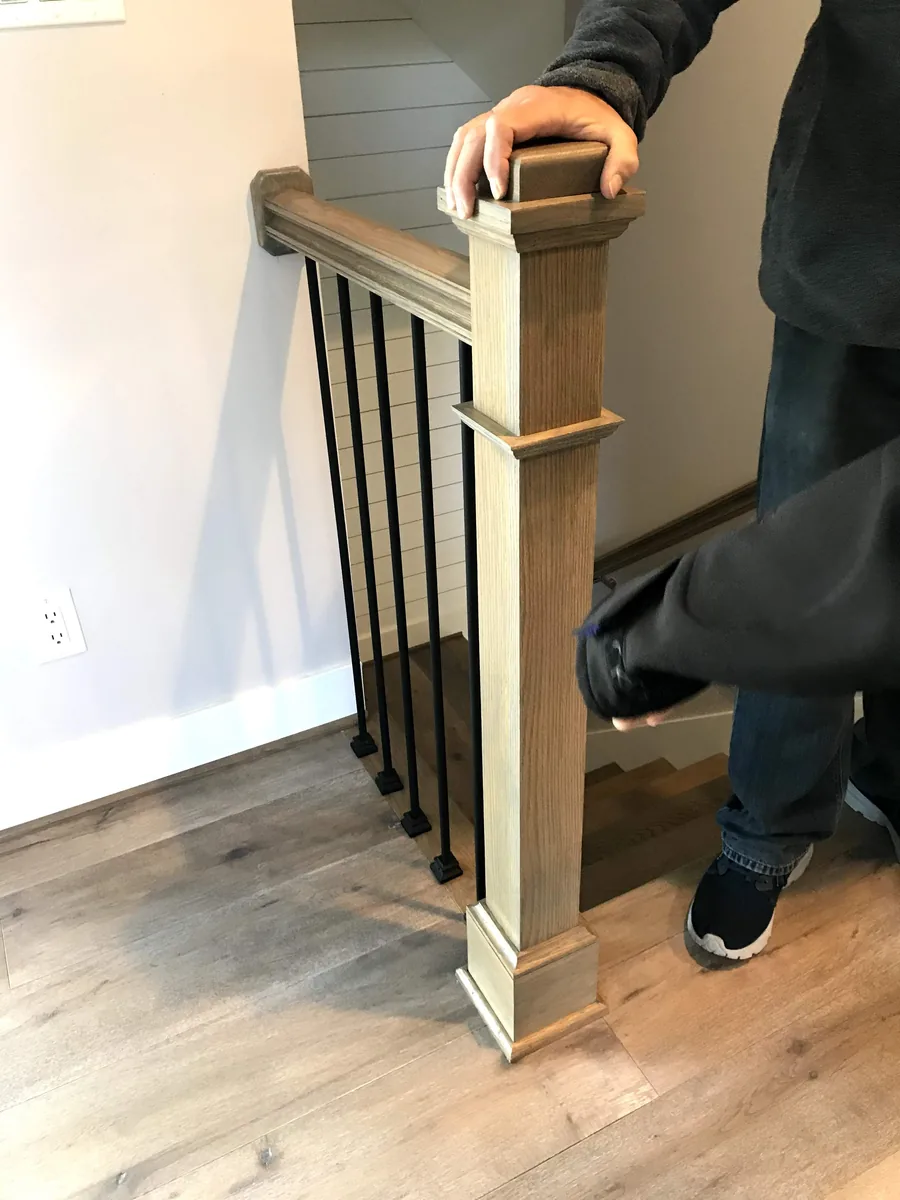 Box newel post and handrail with black metal balusters at the top of a staircase in Vanier, Ottawa
